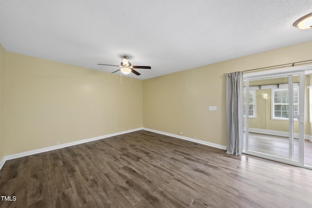 spare room with a textured ceiling, wood finished floors, baseboards, and ceiling fan