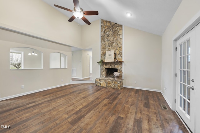 unfurnished living room featuring visible vents, ceiling fan with notable chandelier, wood finished floors, a stone fireplace, and baseboards