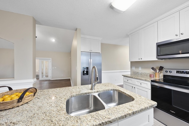 kitchen featuring a sink, white cabinets, light stone counters, and stainless steel appliances