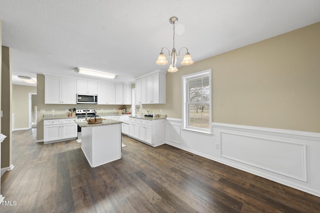 kitchen featuring visible vents, a center island, appliances with stainless steel finishes, white cabinets, and an inviting chandelier