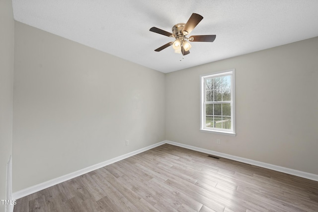 empty room with visible vents, a ceiling fan, a textured ceiling, wood finished floors, and baseboards