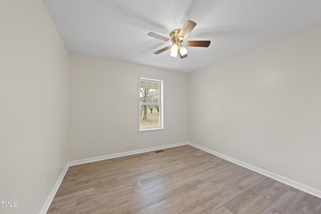 unfurnished room featuring a textured ceiling, baseboards, light wood-type flooring, and ceiling fan