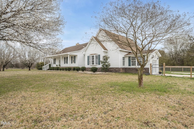 view of property exterior featuring fence, roof with shingles, covered porch, a chimney, and a yard