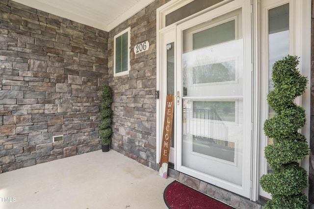 doorway to property with stone siding and covered porch