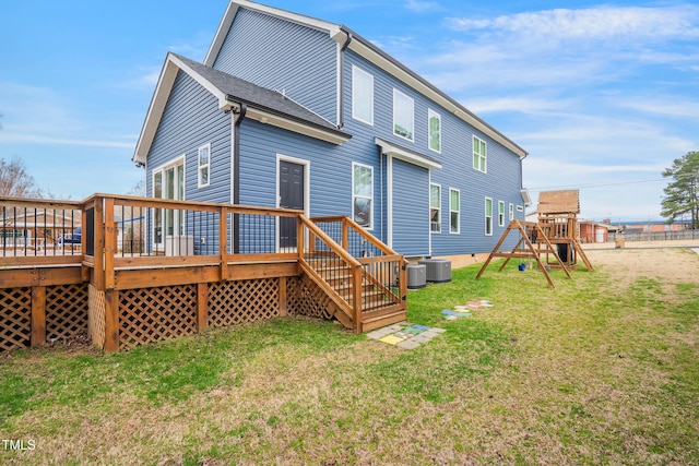 rear view of property with a deck, central AC unit, a playground, and a lawn