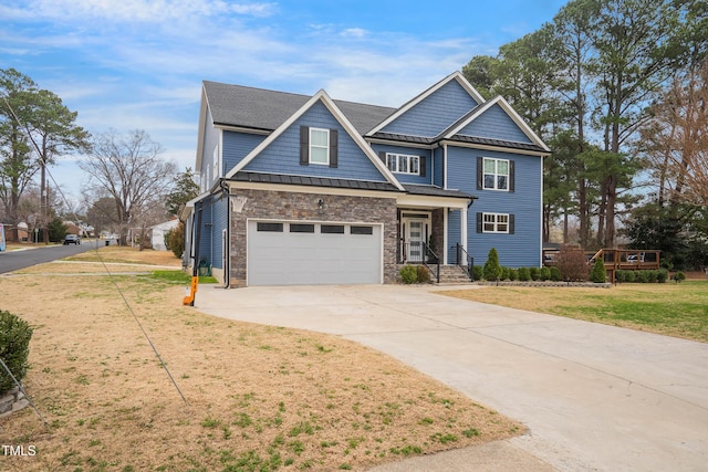 view of front of property with a front lawn, concrete driveway, stone siding, an attached garage, and a standing seam roof