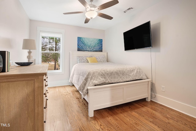 bedroom featuring a ceiling fan, wood finished floors, visible vents, and baseboards