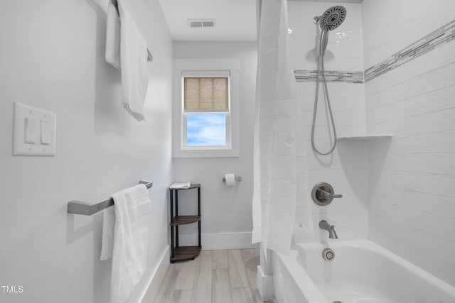 bathroom with visible vents, baseboards, wood finished floors, and shower / bath combination with curtain