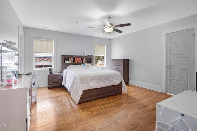 bedroom with visible vents, baseboards, light wood-style floors, and ceiling fan