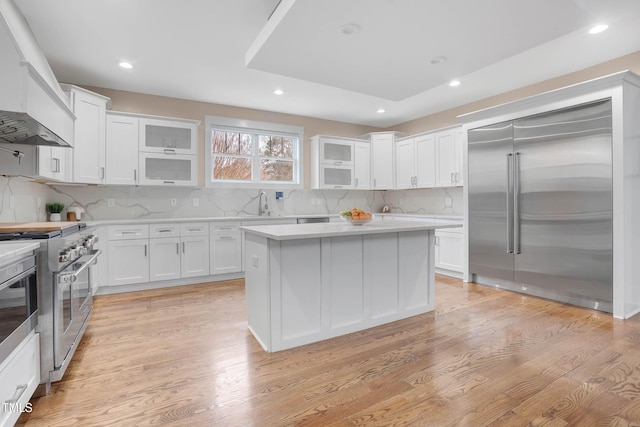 kitchen featuring light wood finished floors, white cabinets, high quality appliances, and light countertops