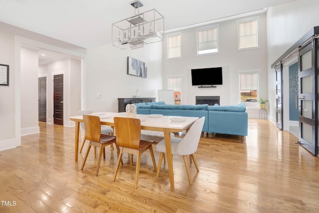 dining area with a fireplace, a healthy amount of sunlight, baseboards, and light wood finished floors