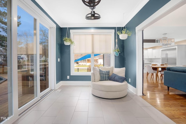 sitting room featuring wood finished floors, baseboards, a notable chandelier, and ornamental molding