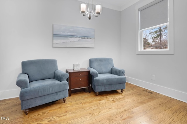 sitting room with a chandelier, crown molding, baseboards, and wood finished floors