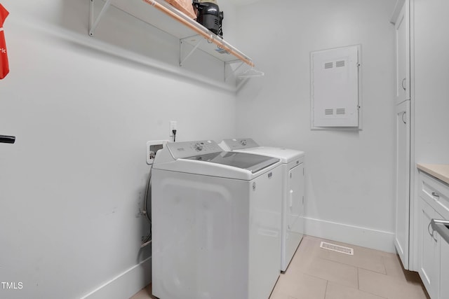 washroom featuring visible vents, baseboards, washer and clothes dryer, light tile patterned floors, and cabinet space