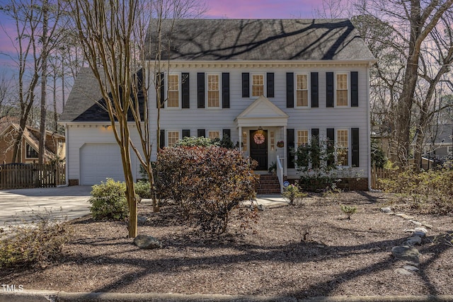 colonial house featuring fence, a garage, and driveway