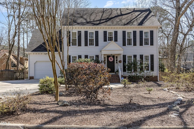 colonial home featuring a garage, driveway, and fence