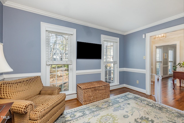 sitting room featuring a chandelier, baseboards, wood finished floors, and ornamental molding