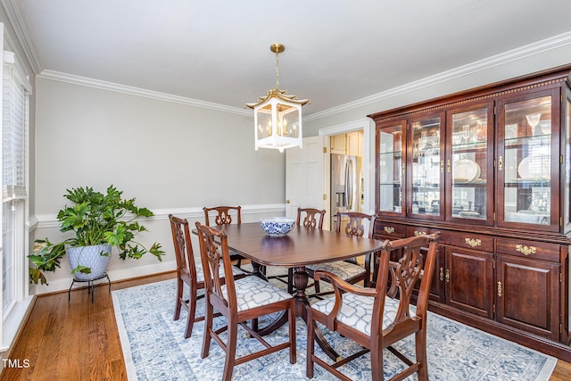 dining area featuring light wood-style floors, an inviting chandelier, and ornamental molding