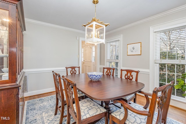 dining area featuring crown molding, a notable chandelier, wood finished floors, and baseboards