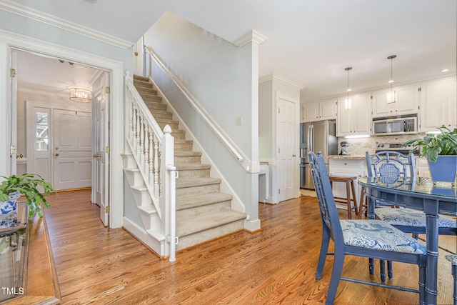 dining space featuring stairway, light wood-style flooring, and crown molding