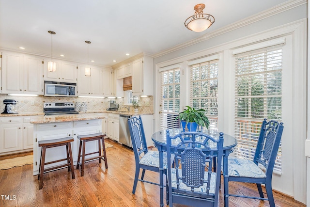 kitchen featuring white cabinetry, light wood-style flooring, backsplash, and appliances with stainless steel finishes