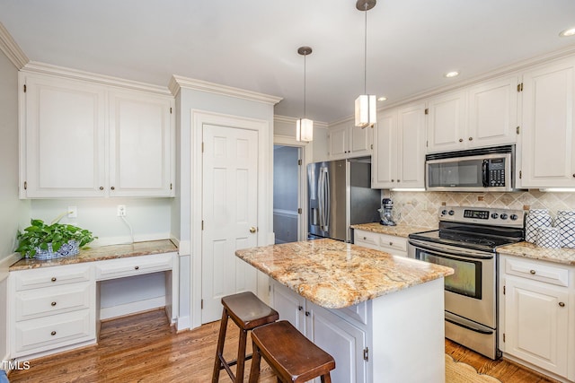 kitchen featuring light wood-type flooring, a kitchen island, backsplash, white cabinetry, and stainless steel appliances