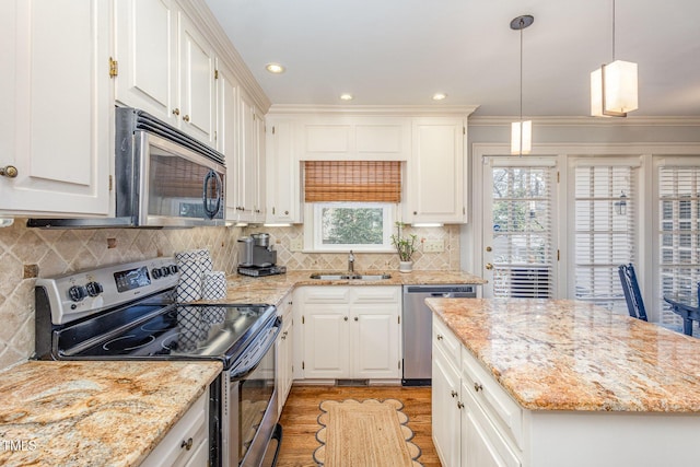 kitchen featuring white cabinets, light stone countertops, appliances with stainless steel finishes, and a sink