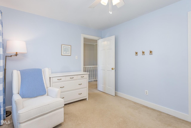 living area featuring baseboards, light colored carpet, and a ceiling fan