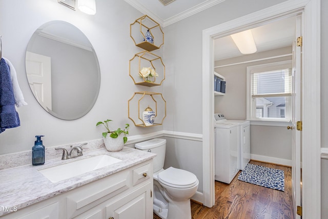 bathroom with toilet, wood finished floors, separate washer and dryer, crown molding, and vanity