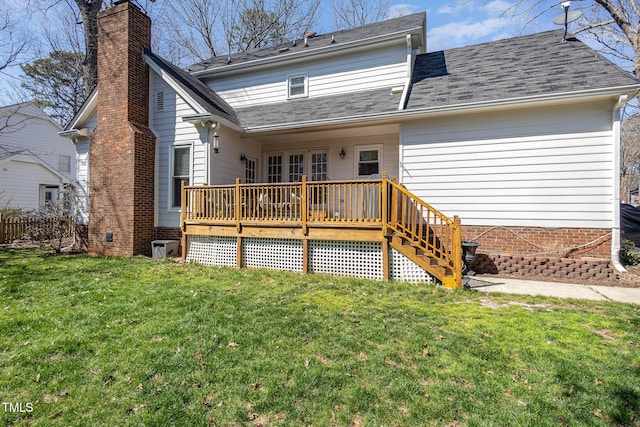 rear view of property featuring a yard, a deck, a chimney, and a shingled roof