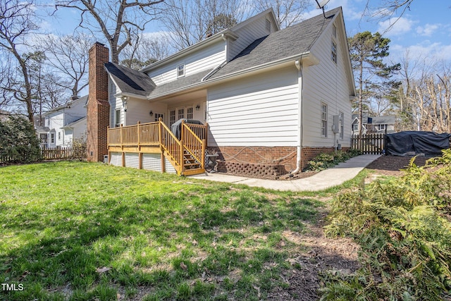 rear view of property featuring a chimney, a wooden deck, a yard, and fence