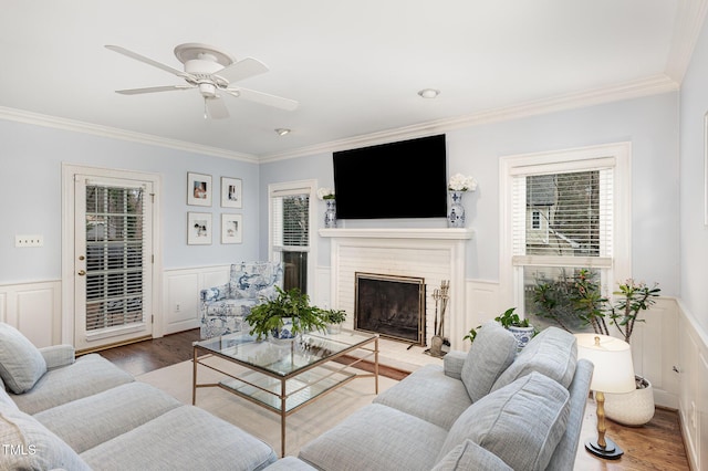 living area featuring wainscoting, wood finished floors, and crown molding