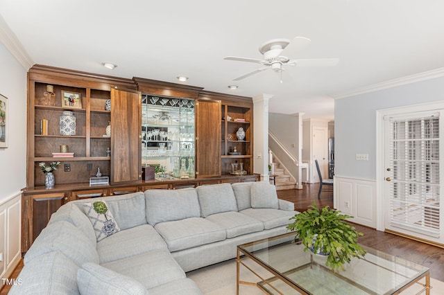 living area with crown molding, stairway, wood finished floors, and a wainscoted wall