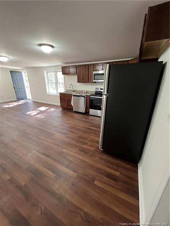 kitchen with dark wood-style floors, open floor plan, stainless steel appliances, light countertops, and baseboards