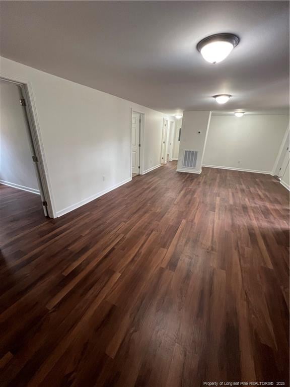 unfurnished living room with dark wood finished floors, baseboards, and visible vents