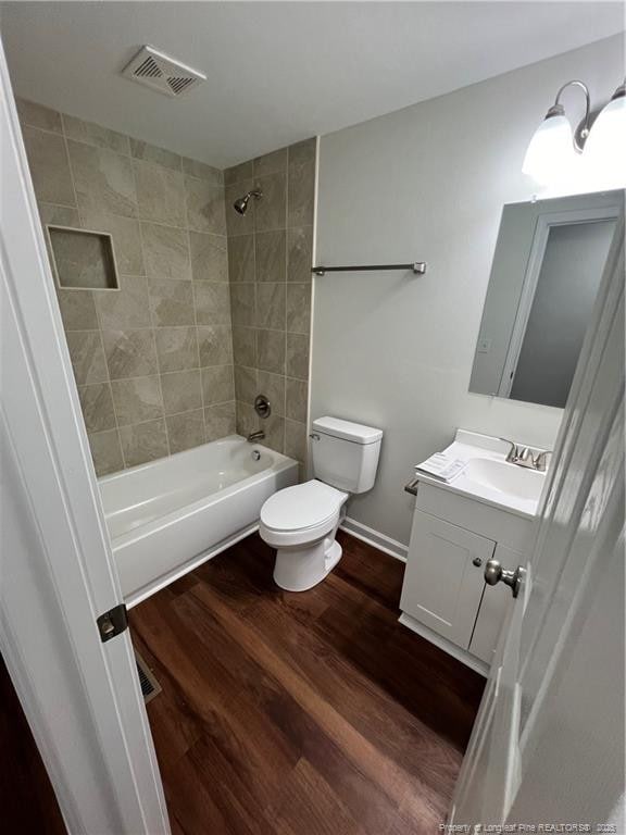 bathroom with visible vents, toilet, wood finished floors, vanity, and shower / bathtub combination