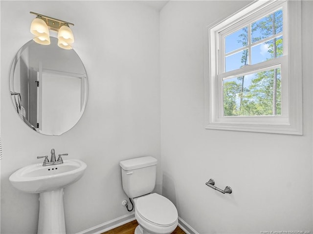 half bathroom featuring a sink, baseboards, and toilet