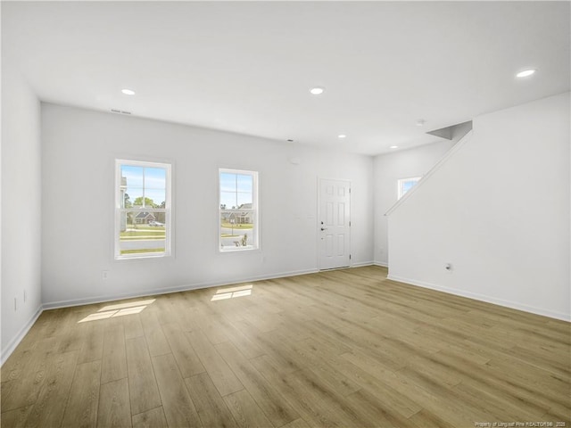 unfurnished living room featuring plenty of natural light, recessed lighting, light wood finished floors, and baseboards