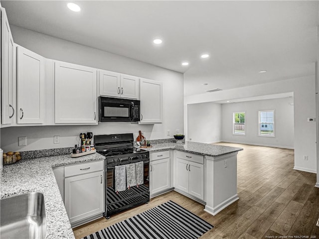kitchen featuring visible vents, black appliances, light wood finished floors, a peninsula, and white cabinetry
