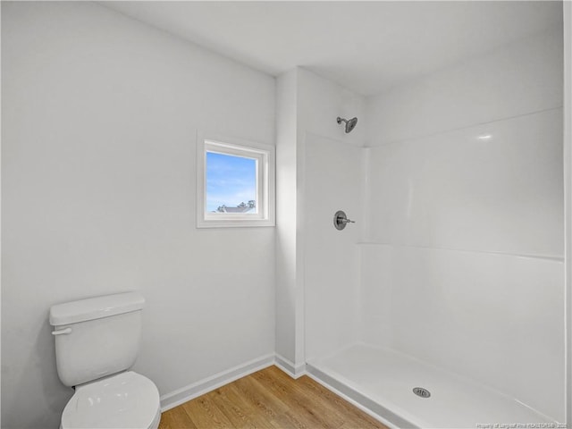 bathroom with baseboards, walk in shower, toilet, and wood finished floors