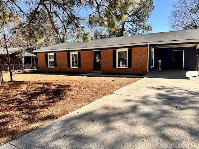 ranch-style house featuring an attached carport, concrete driveway, and brick siding