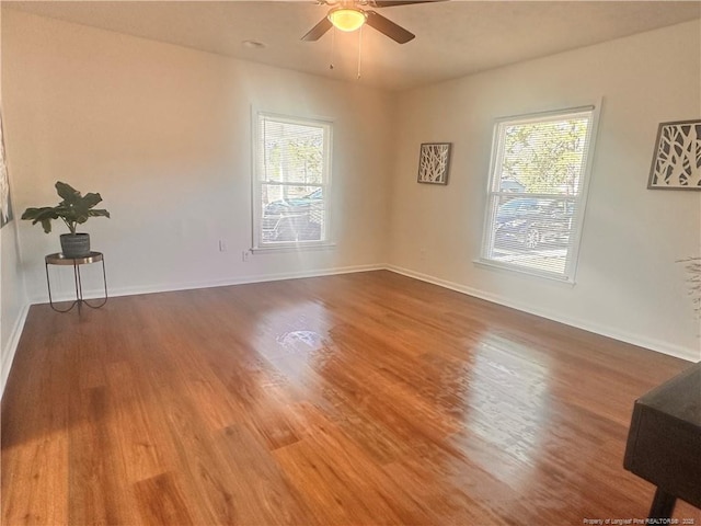 empty room featuring baseboards, wood finished floors, and a ceiling fan