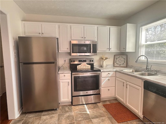 kitchen with white cabinetry, light countertops, appliances with stainless steel finishes, and a sink