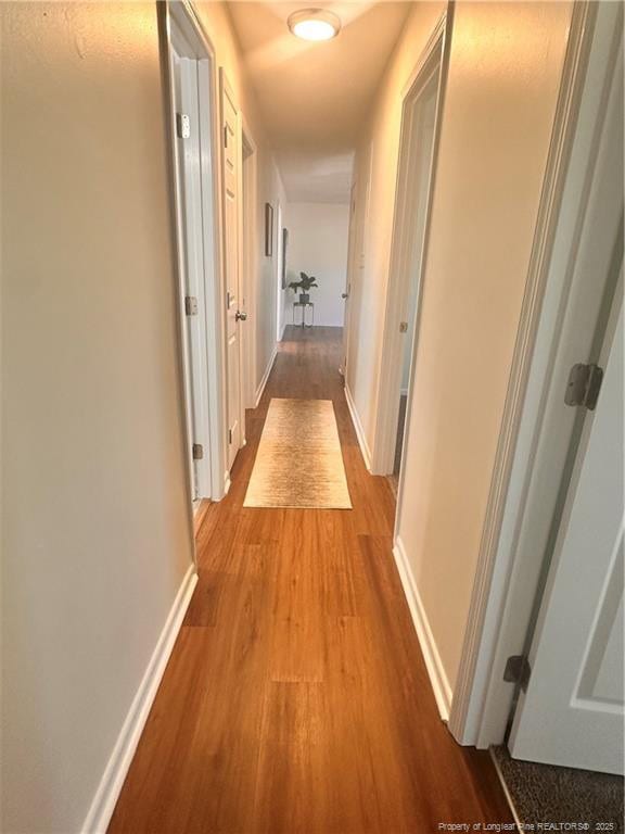 hallway featuring baseboards and wood finished floors