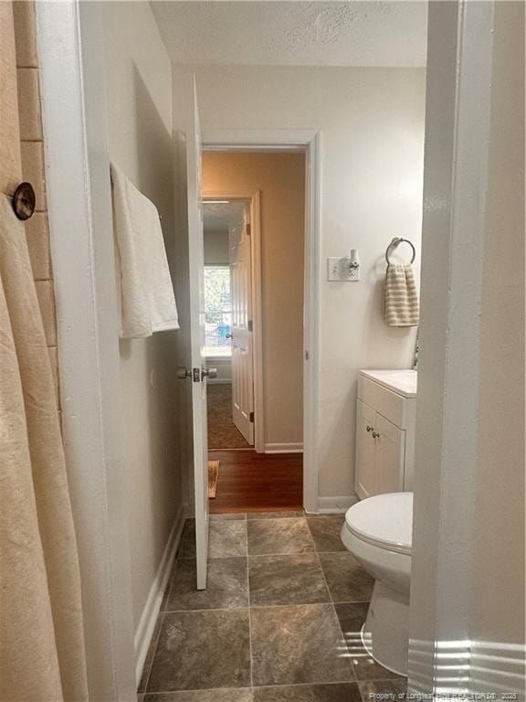 bathroom featuring vanity, toilet, baseboards, and a textured ceiling