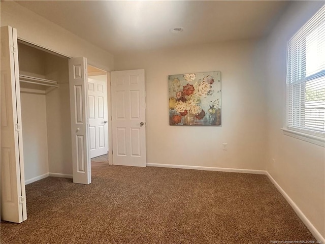 unfurnished bedroom with a closet, dark carpet, and baseboards