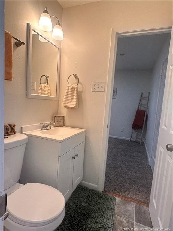 bathroom with toilet, vanity, and baseboards