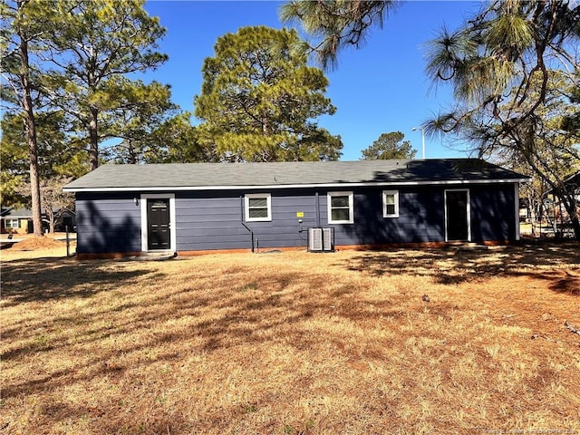 back of property featuring central AC unit and a yard