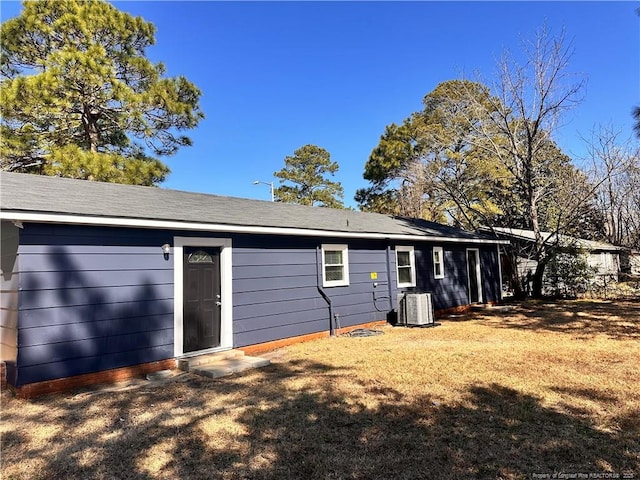 back of property featuring a lawn and central AC