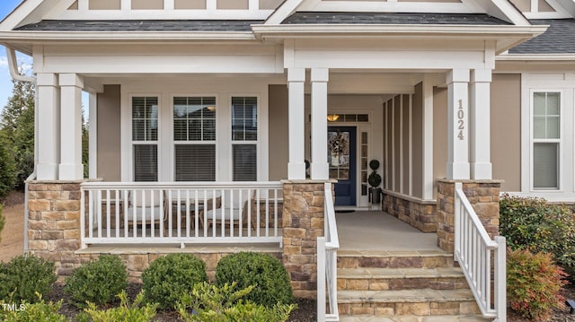 property entrance with stone siding, a porch, and roof with shingles